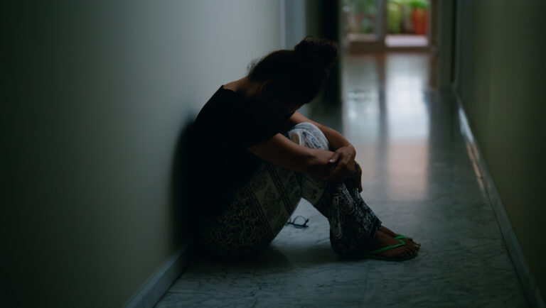 Middle age hispanic woman suffering for domestic violence with bruise on eyes sitting on floor at home