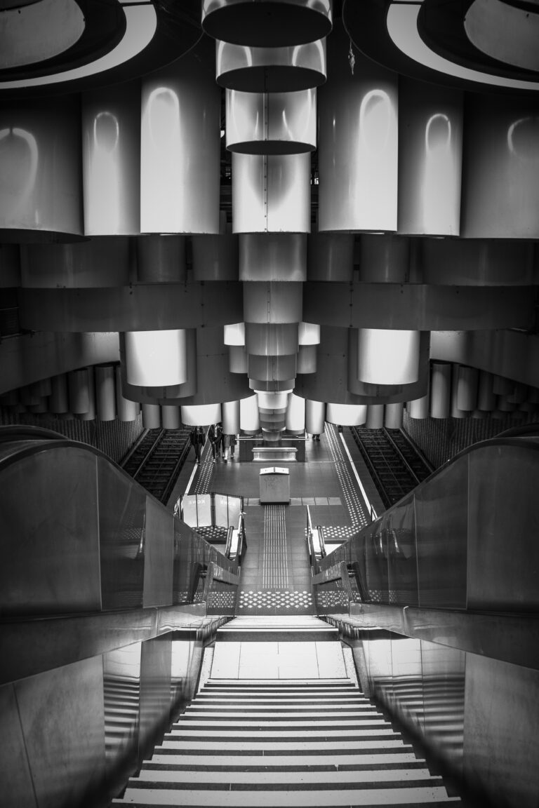 Vertical grayscale shot of a modern metro station with escalators in Brussels, Belgium